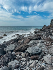 Fototapeta na wymiar Scenic view of idyllic volcanic black stone beach Praia Garajai, Canico, Madeira island, Portugal, Europe. Sea waves smashing at shoreline of majestic Atlantic Ocean. Dramatic sky. Coastal landscape