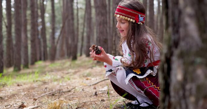 Bulgarian woman young girl in ethnic folklore embroidery costume walk in beautiful forest in Rhodopes mountains, Bulgaria