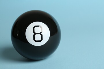 One magic eight ball on light blue background, space for text