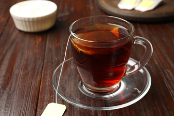 Brewing tea. Glass cup with tea bag on wooden table, closeup