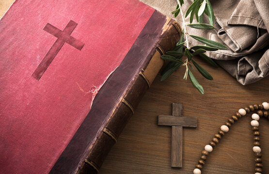 Bible on wooden table with cross olive leaves and fabric