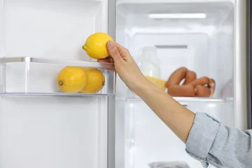 Fotobehang Young woman taking lemon out of refrigerator, closeup © New Africa