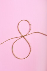 Golden jute twine in the shape of eight as symbol of symbol of women's equality. International women's day concept. Close up, copy space for text, background.