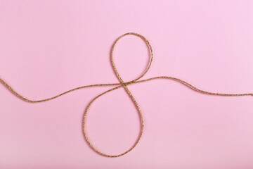 Golden jute twine in the shape of eight as symbol of symbol of women's equality. International women's day concept. Close up, copy space for text, background.