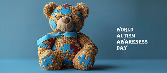 World Autism Awareness Day. Teddy bear with blue ribbon on blue background.