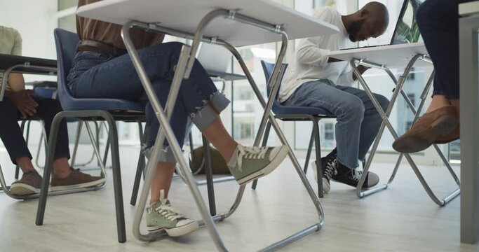 Legs, classroom and students at school for test or education for development, learning or future. School kids, shoes and people studying at table for writing test at desk in university or college