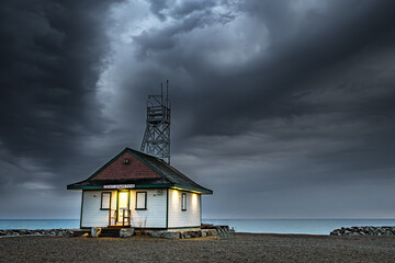 dark moody thunder storm clouds fill the sky over a wooden lifegaurd station shot after sundown on kew beach in toronto room for text