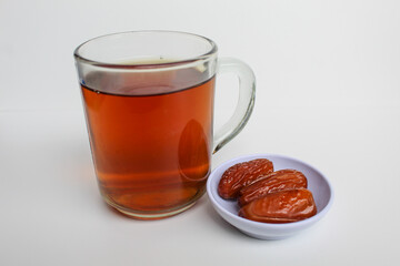 Three pieces of Deglet noor or deglet nour or date palm or dates, with a glass of tea, isolated on white background