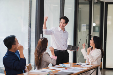 Successful young Asian business team feeling excited and happy from the good news.
