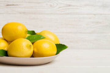 Fresh cutted lemon and whole lemons over round plate on colored background. Food and drink ingredients preparing. healthy eating theme top view vith copy space