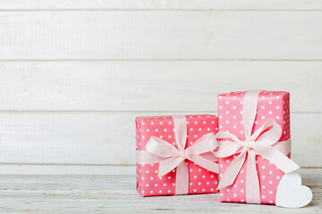 gift box with red bow and red heart on colored background. Perspective view. Flat lay