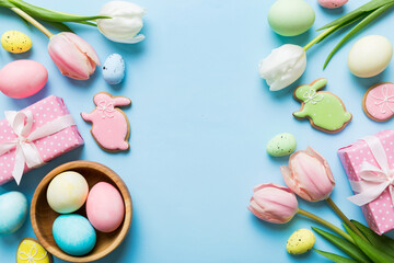 Fototapeta premium Easter frame with eggs, gift box and tulip on a colored background. The minimal concept. Top view Happy Easter composition. Card with a copy space of the place for the text