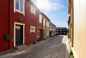 Fototapeta na wymiar Warm sunbeams grace a cozy street in Roros, casting light on the colorful facades of the historic wooden houses that embody the town's rich cultural tapestry