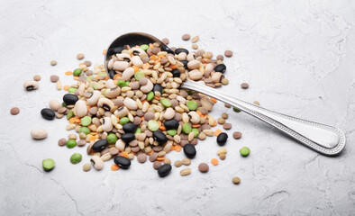 Dried legumes and grains, beans, lentils, barley and peas, vegetable soup mix with old spoon on white plaster background, space for text, close-up. - 747368932