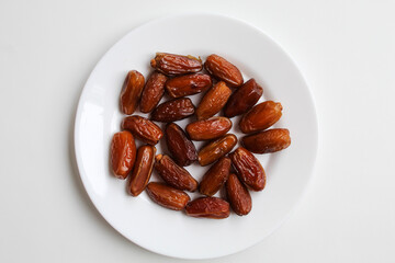Deglet noor or deglet nour or date palm or dates, in a transparent white plate, isolated on white...