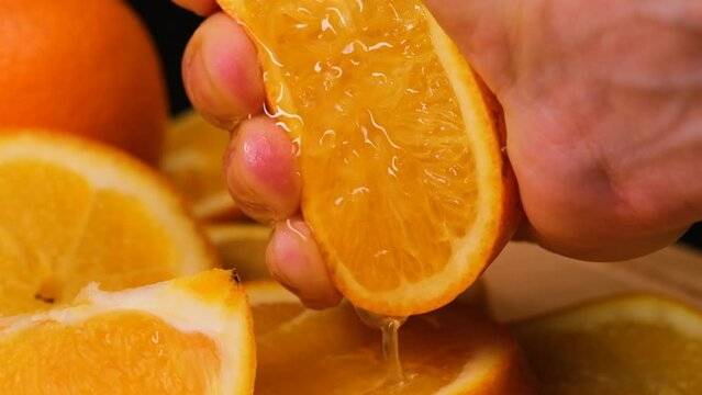 Squeezing out the fresh orange. A picture of a person's hand squeezing orange juice. Hand squeezing half fresh oranges on the orange press with pulp. hand holding fresh raw citrus.