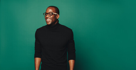 Confident young man with stylish eyeglasses and trendy green background