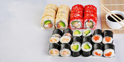 Popular types of sushi, soy sauce and chopsticks. Set of sushi roll on a gray background.