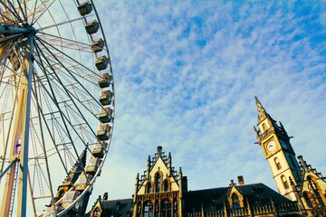 Fun fair wheel with sunny sky and clouds with old architecture in Ghent Belgium