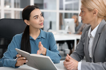 Lawyers with notebook working together at table in office, selective focus