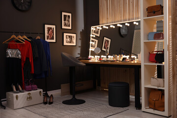 Chair, clothes rack and stylish mirror on dressing table in makeup room