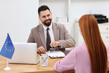 Immigration to European Union. Embassy worker approving visa application form to woman in office