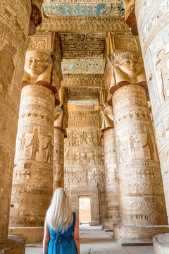 Dendera, Egypt- A blonde haired woman looks up at the interior of the hypostyle hall in the Temple of Dendera.