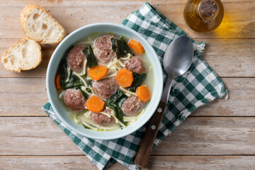 Italian Wedding Soup with meatballs and spinach on wooden table. Top view