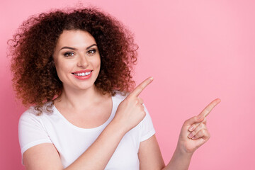 Obraz premium Photo of pleasant woman with perming coiffure dressed white t-shirt directing at proposition empty space isolated on pink color background