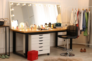 Makeup room. Stylish dressing table with mirror, chair and clothes rack