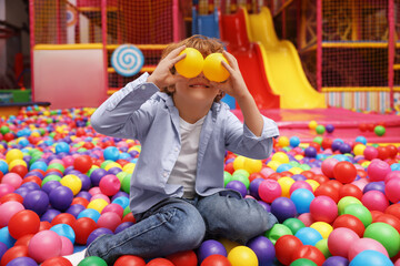 Fototapeta na wymiar Happy little boy holding colorful balls in ball pit