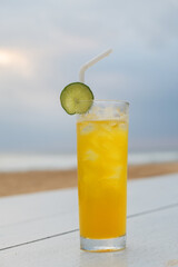 Glass of orange cocktail decorated lime slice on table at beach bar.