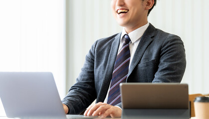 笑顔でパソコンを使う男性ビジネスマン