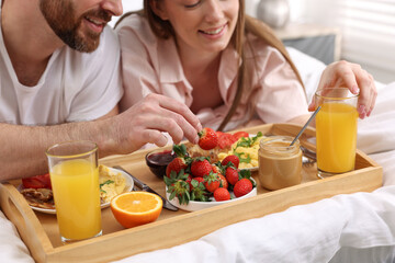 Obraz na płótnie Canvas Happy couple eating tasty breakfast on bed, closeup