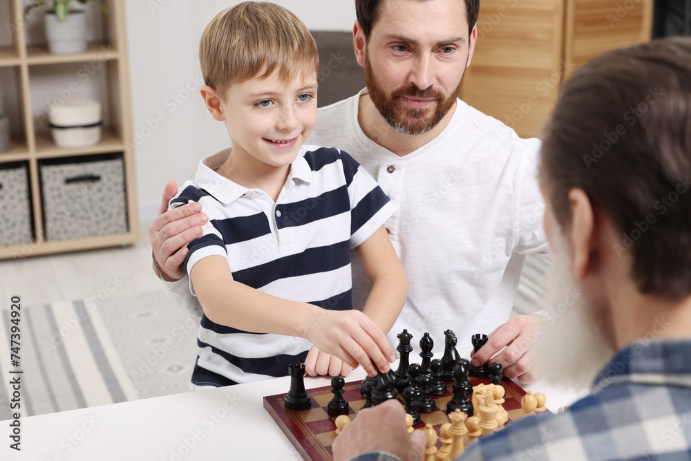 Sticker Family playing chess together at table in room