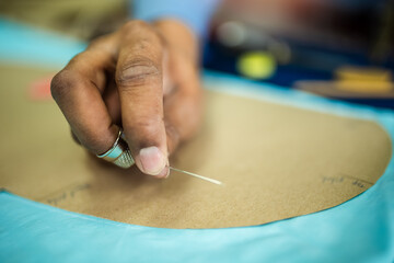 Young African American tailor sewing with a thread.