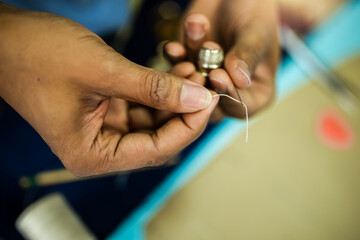 Young African American tailor sewing with a thread.
