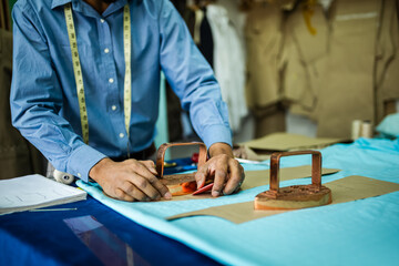 Young African American tailor glueing down material in his own atelier.