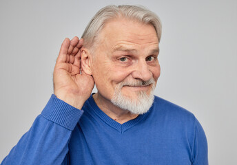 Senior man listening sound with hand near ear for hearing check-up. Hearing test concept