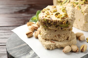 Pieces of tasty halva with pistachios on table, closeup. Space for text