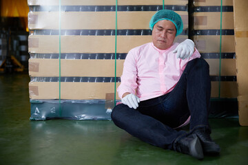 male factory worker feeling tired and exhausted from overworked in the beverage factory