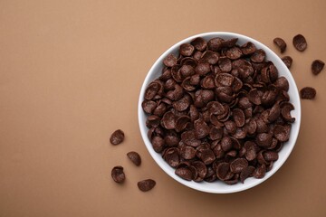 Breakfast cereal. Chocolate corn flakes in bowl on brown table, top view. Space for text