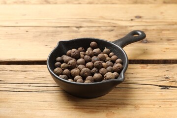 Dry allspice berries (Jamaica pepper) in dish on wooden table