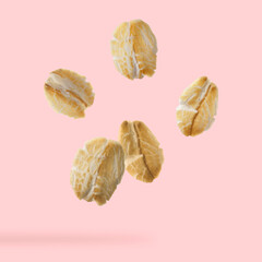 Rolled oat flakes falling on pink background