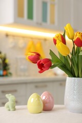 Bouquet of tulips and Easter decorations on white table indoors