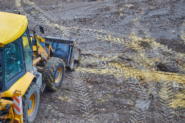 A yellow bulldozer stands on a cleared land plot, the beginning of construction