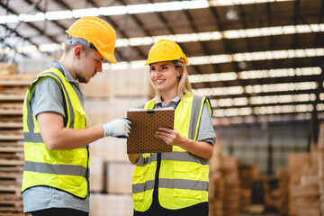 Man and woman workers with clipboard discussing working and checking stock inventory wood plank material for making wooden pallet products at warehouse industrial factory, woodwork production
