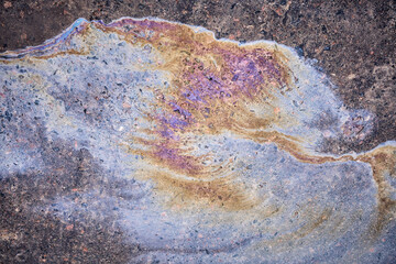 Textured stain of fuel or oil on wet asphalt on a rainy day. The concept of environmental pollution