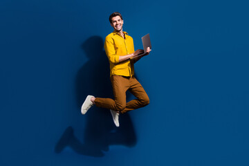Full length photo of nice young male jump hold netbook marketer wear trendy yellow garment isolated...