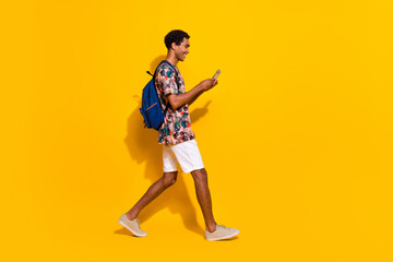 Fototapeta na wymiar Full body length photo of strolling tourist summertime outfit using smartphone check actual maps isolated on yellow color background